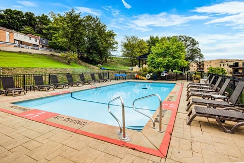 A pool with a red border and a sign that says "Do Not Dive" is surrounded by lounge chairs.