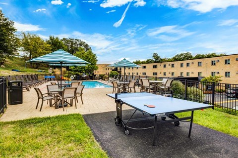 A blue table tennis table is in the middle of a grassy area.