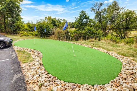 A miniature golf course with a green putting green and two blue flags.