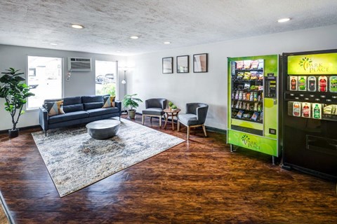 A room with a sofa, chairs, a table, and a vending machine.
