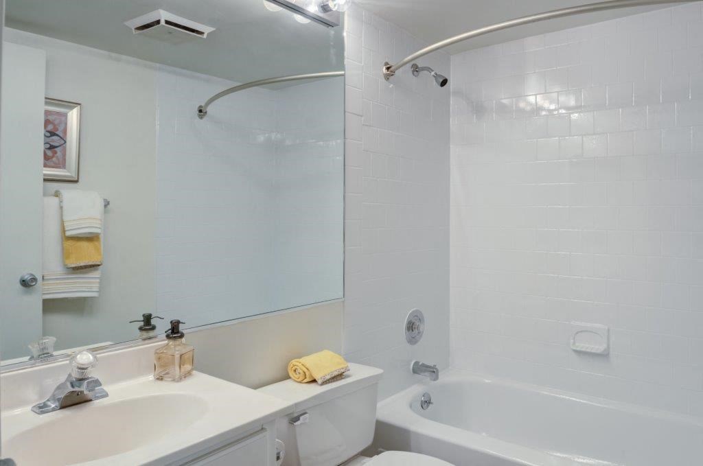 a white bathroom with a tub and a sink and a mirror