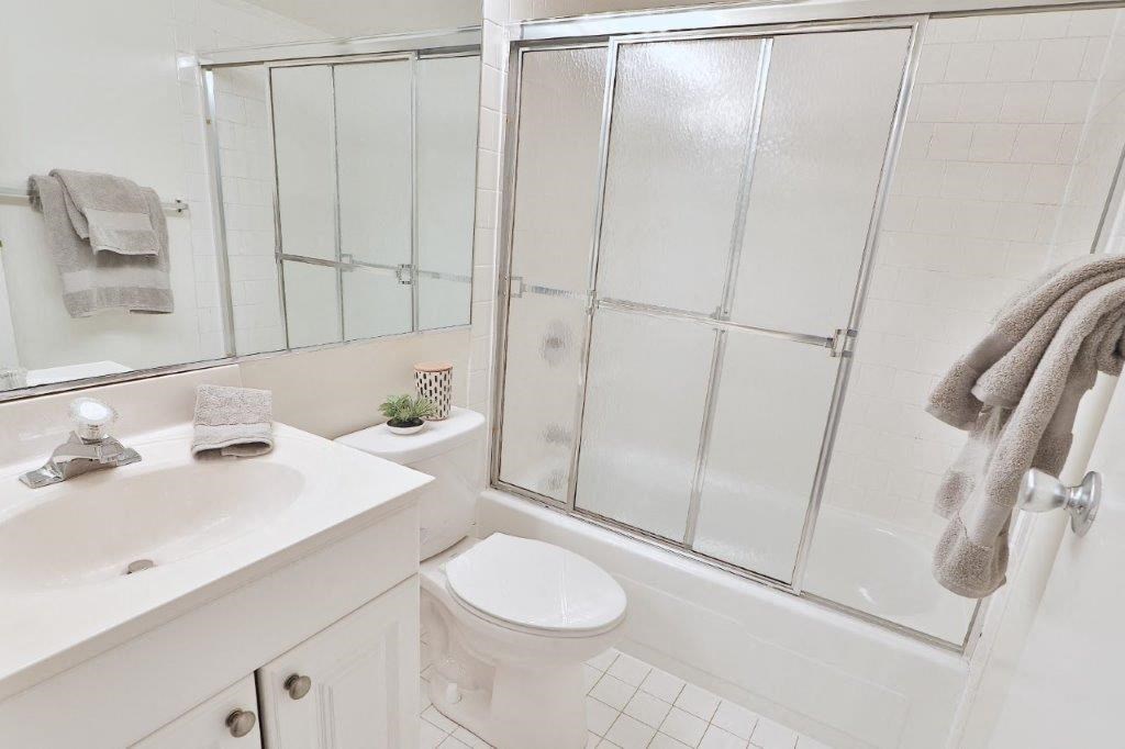 a white bathroom with a shower toilet and sink