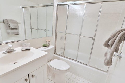 a white bathroom with a shower toilet and sink