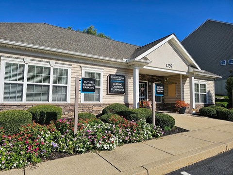 the front entrance of a white building with flowers and bushes