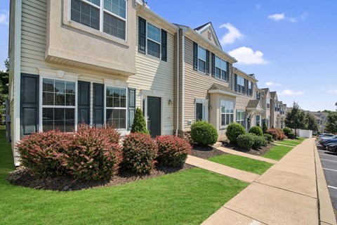 a row of townhomes with a sidewalk and landscaping in front of them