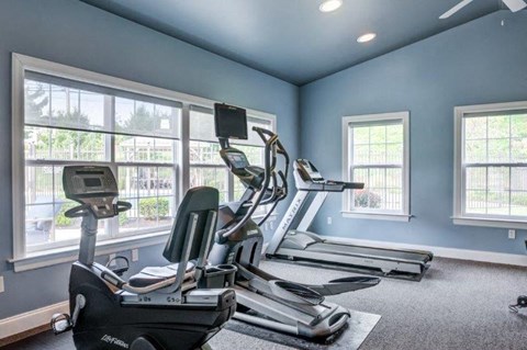 a gym with exercise equipment and large windows