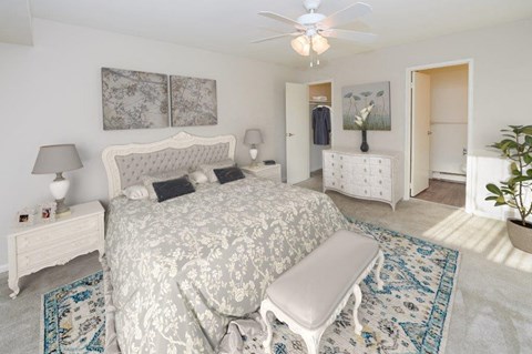 a white bedroom with a bed and a ceiling fan