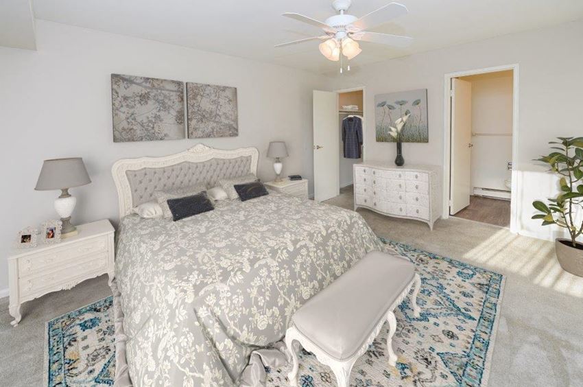 a white bedroom with a bed and a ceiling fan