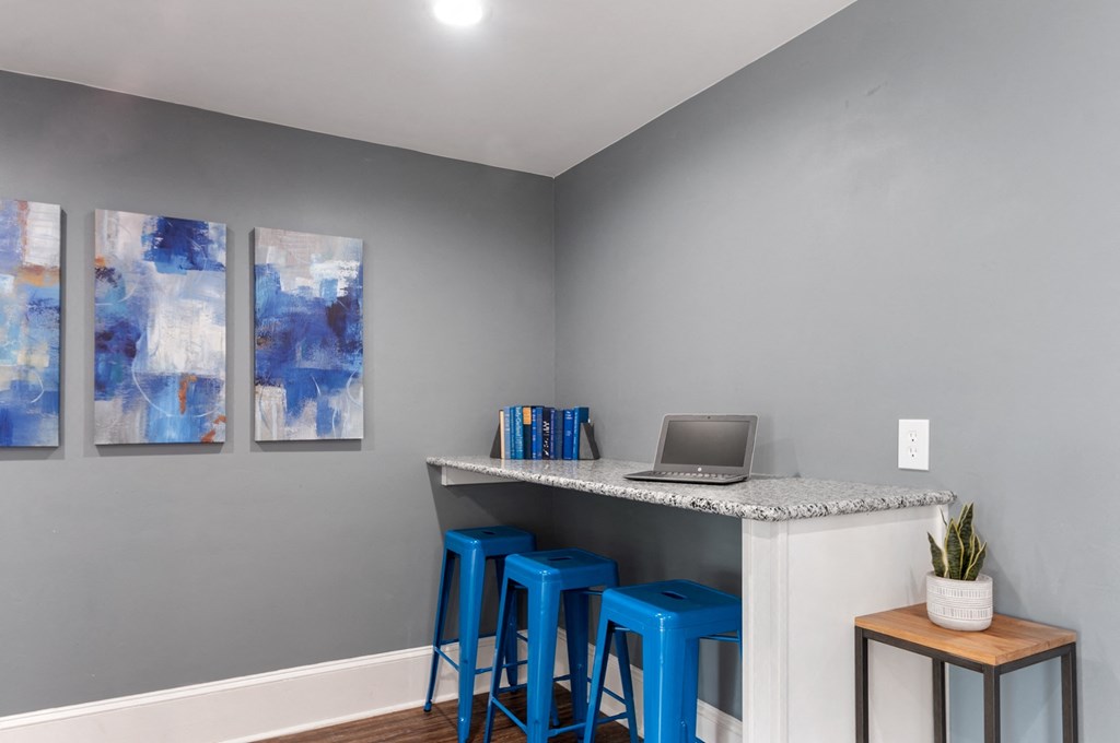 an office with blue stools and a desk with a laptop on it