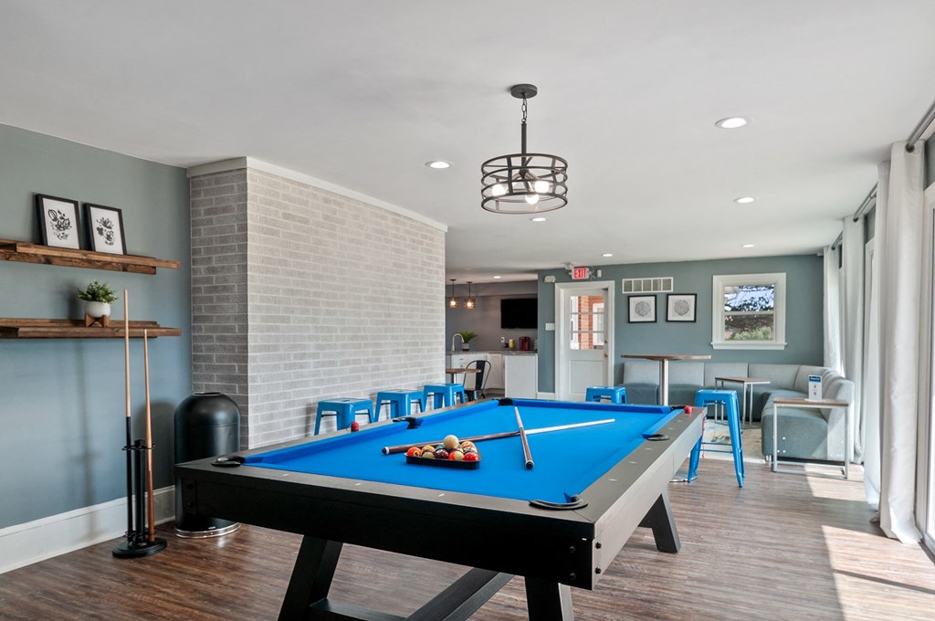 a pool table in a living room with a bar and tables