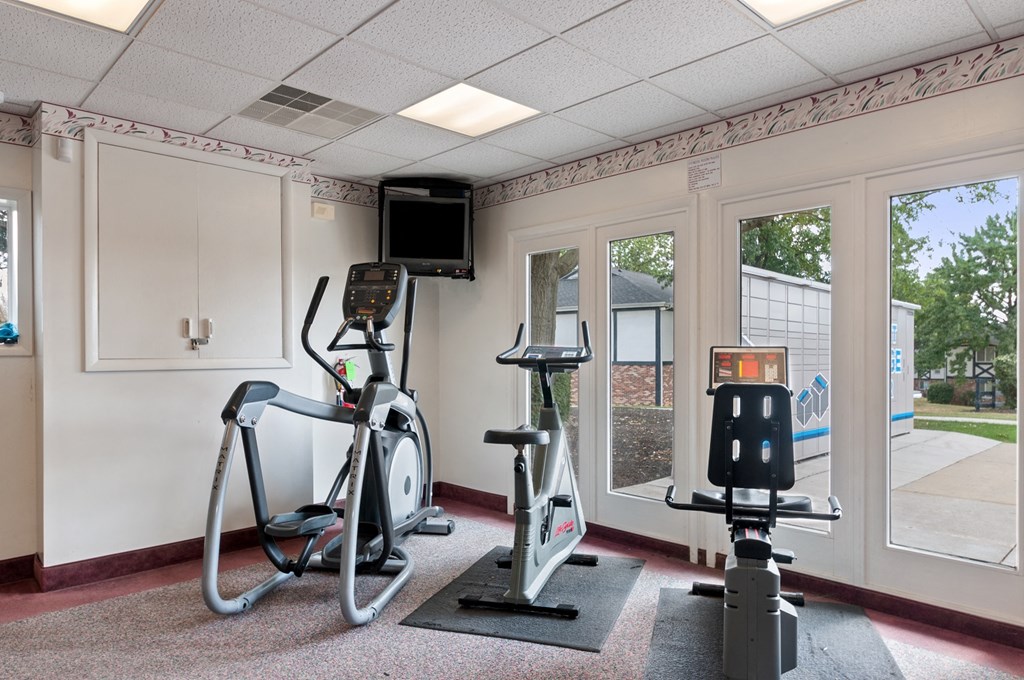 a gym with exercise machines and a tv in the corner