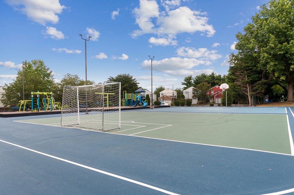 a tennis court with a net and playground in the background
