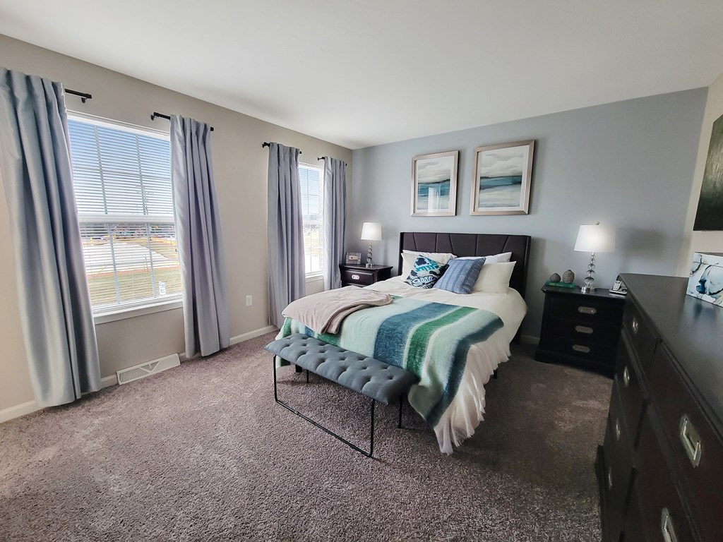 a bedroom with a bed and two windows