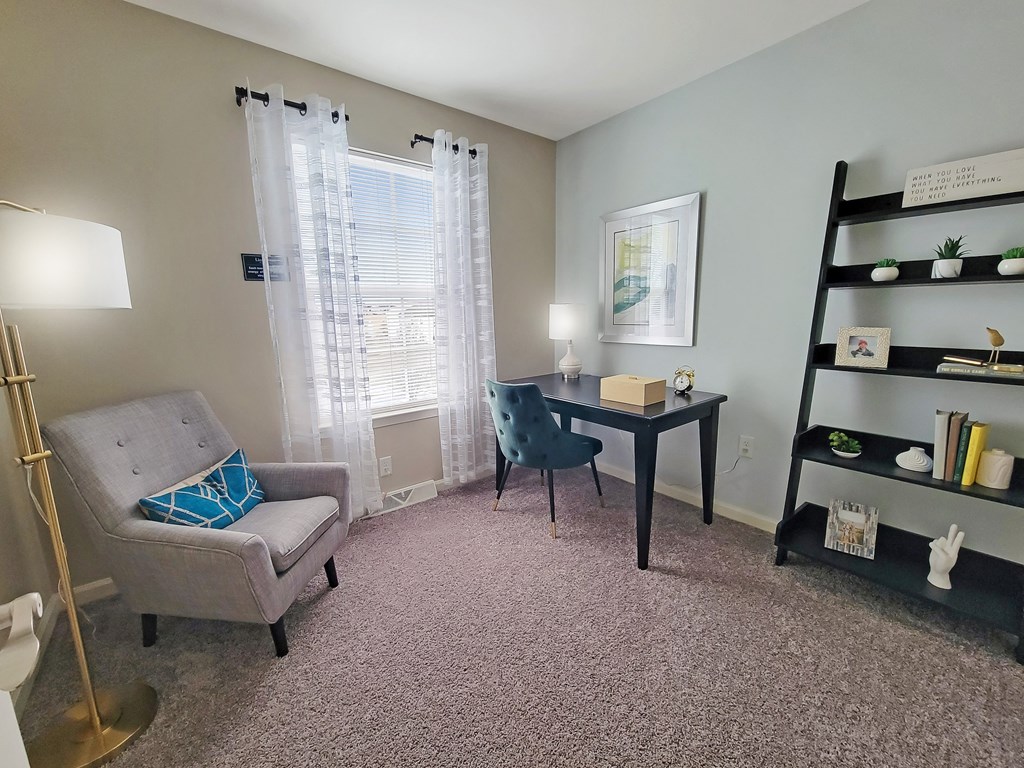 a living room with a chair and a desk and a window