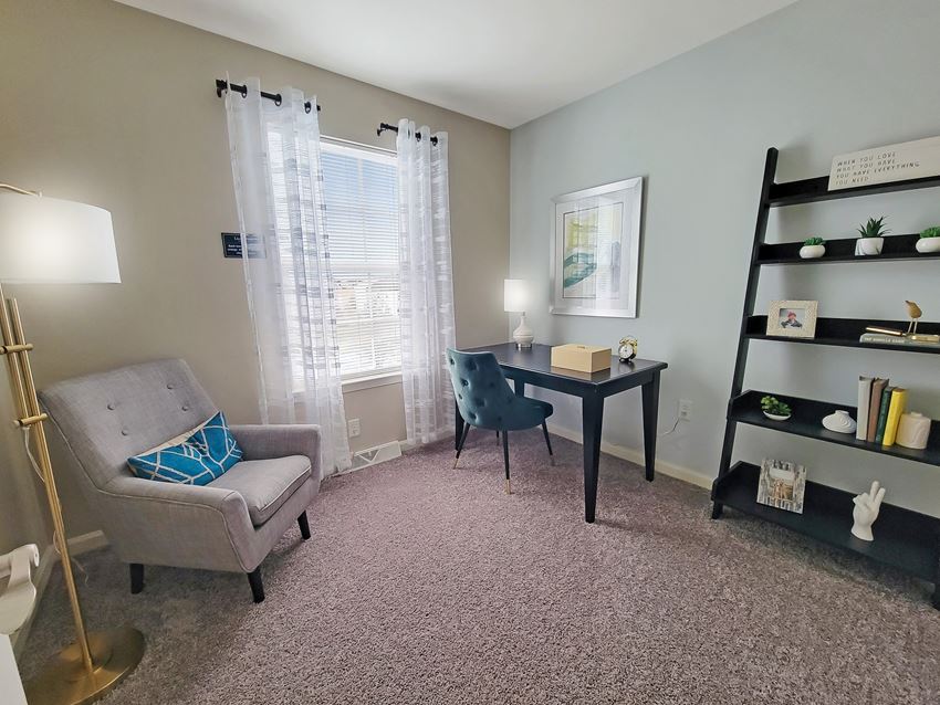 a living room with a chair and a desk and a window