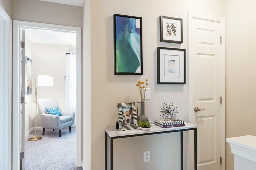 a hallway with pictures on the wall and a table with a vase on it