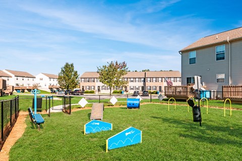 a playground with agility equipment in a yard in front of houses