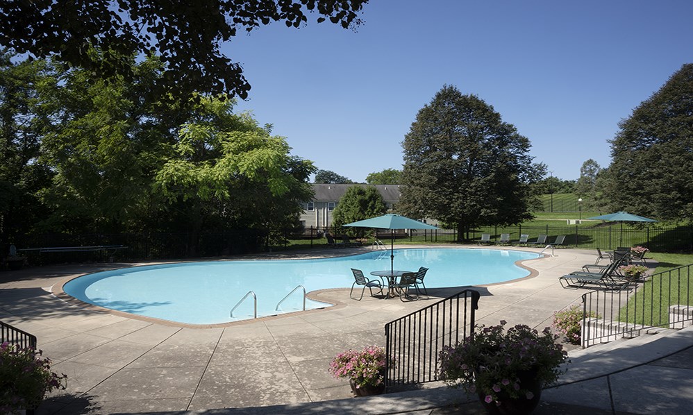 a swimming pool with patio furniture and umbrellas