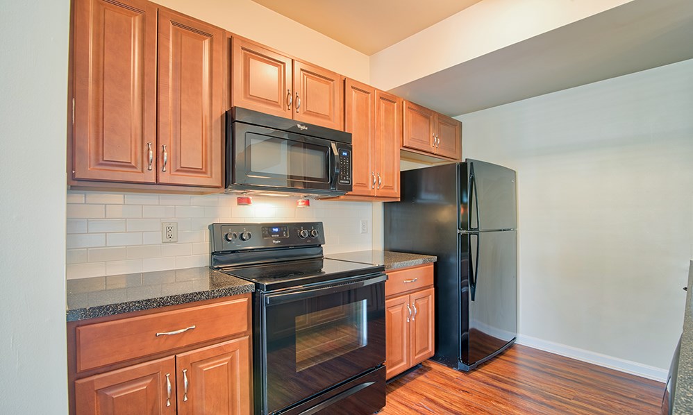 an empty kitchen with wood cabinets and black appliances