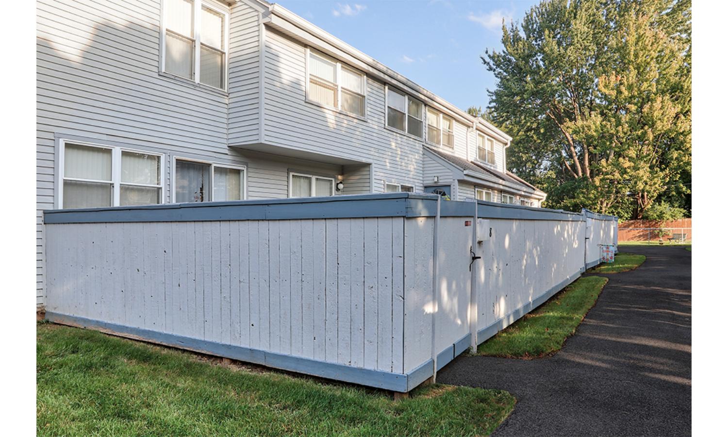 A long white fence runs along the side of a building.