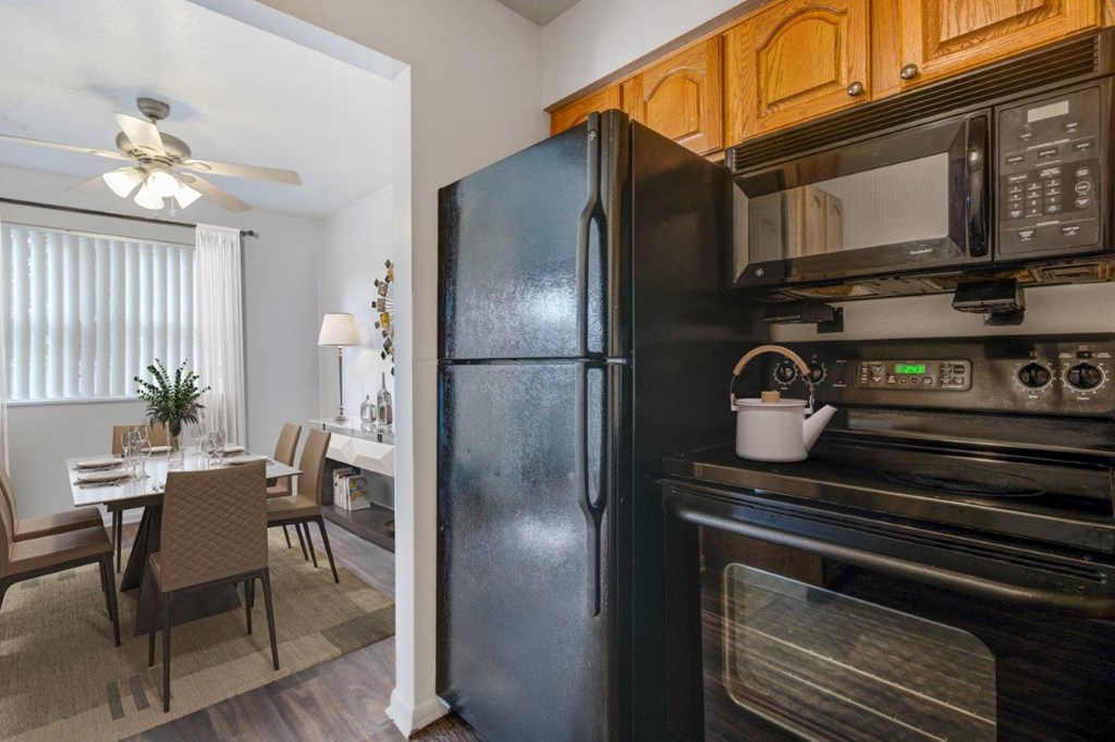 a kitchen with a black refrigerator and microwave and a dining room table