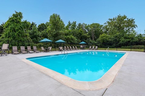a pool with chairs and umbrellas at a resort style pool