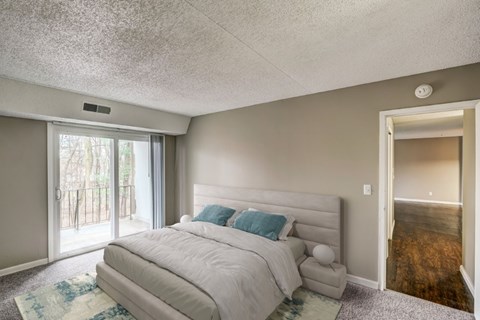 A bedroom with a large bed and a sliding glass door.
