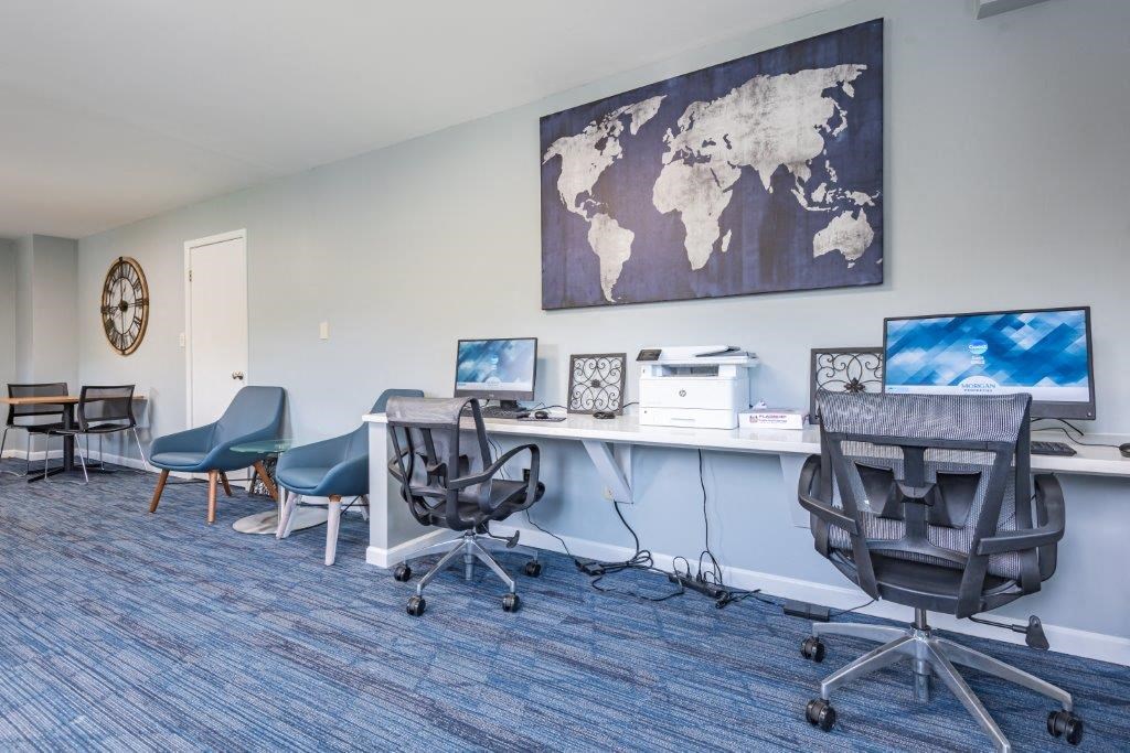 a office with a desk with two computers and a map on the wall