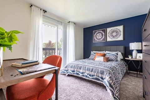 a bedroom with a bed and a desk and a window