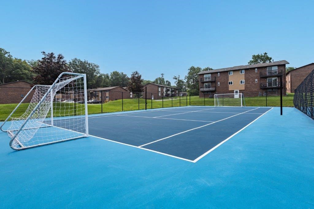 a tennis court with a net in front of an apartment building