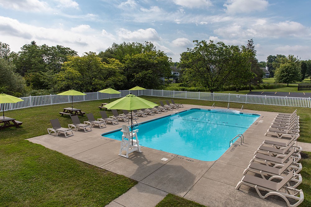 a resort style pool with lounge chairs and a green umbrella