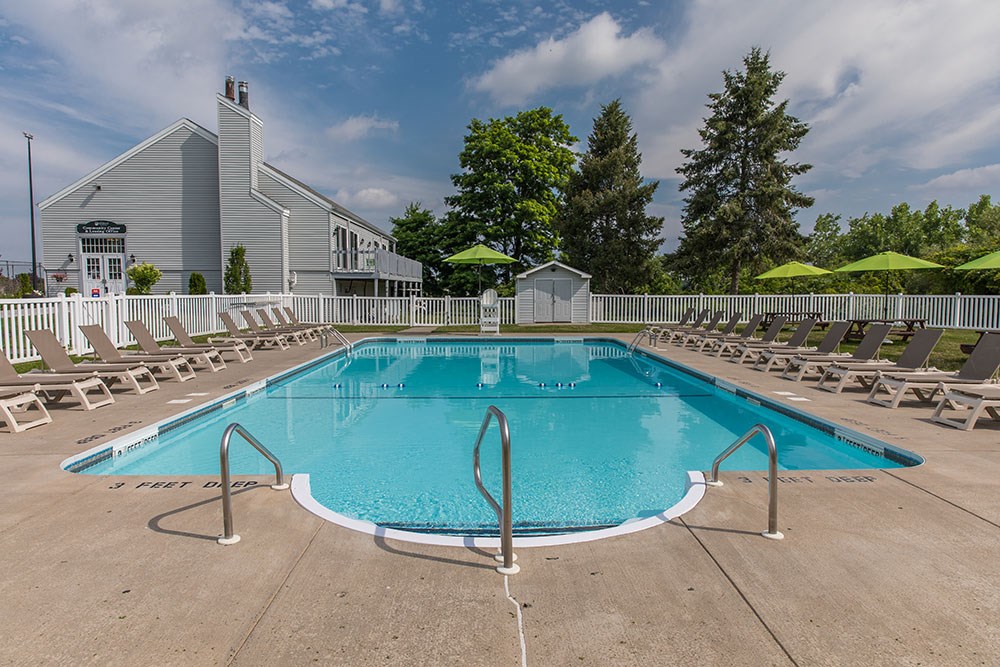 our resort style swimming pool is surrounded by lounge chairs and a building