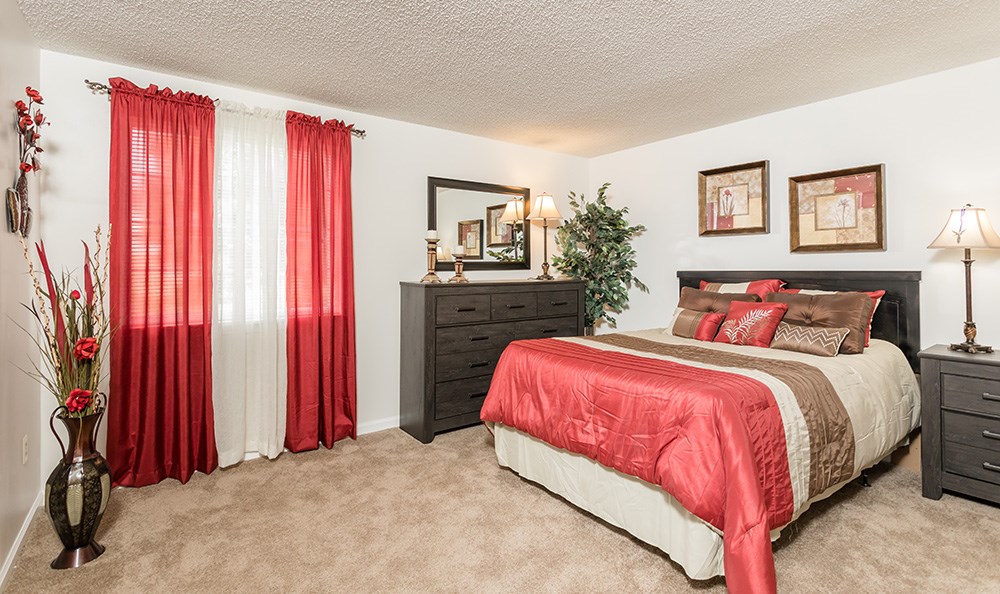 a bedroom with a bed and a window with red curtains