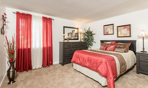 a bedroom with a bed and a window with red curtains