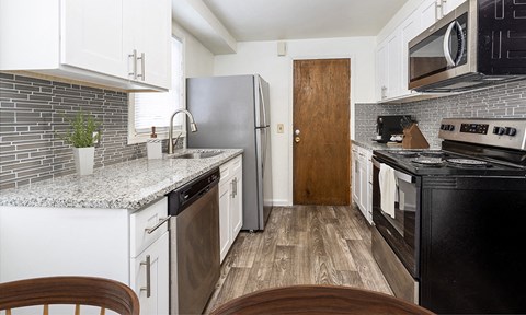 a kitchen with white cabinets and black appliances and a stainless steel refrigerator