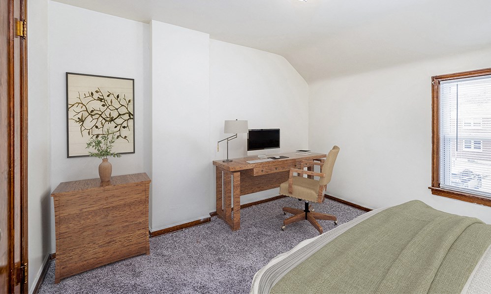 a bedroom with a bed and a desk with a computer