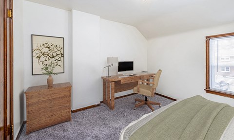 a bedroom with a bed and a desk with a computer
