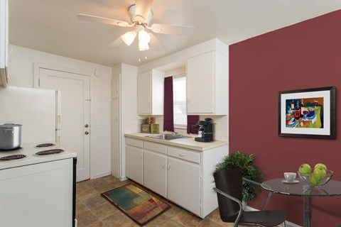 a kitchen with white cabinets and a sink and a red wall