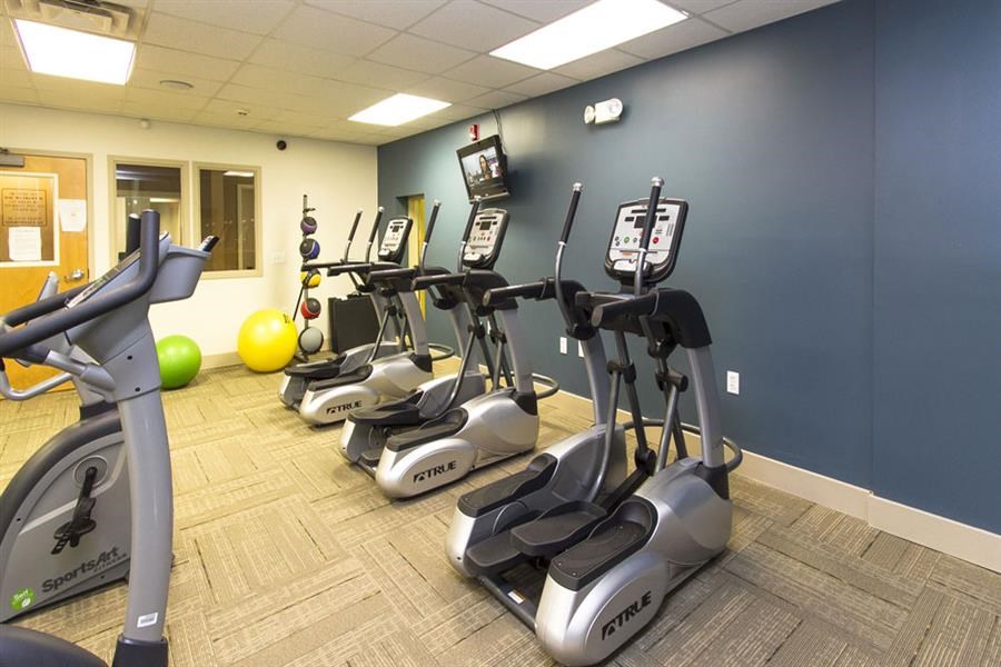 a gym with cardio equipment and weights on the floor