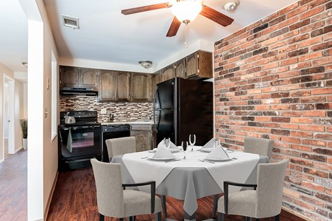 a dining room with a table and a kitchen with a brick wall