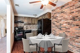 a dining room with a table and a kitchen with a brick wall