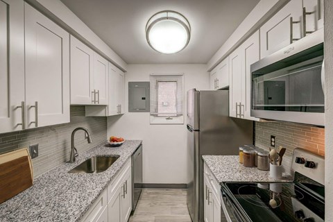 A kitchen with white cabinets and a black stove top.