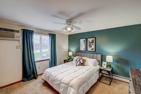 A bedroom with a white bed and a ceiling fan.