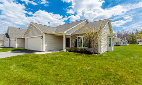 the front of a house with a green lawn and a blue sky
