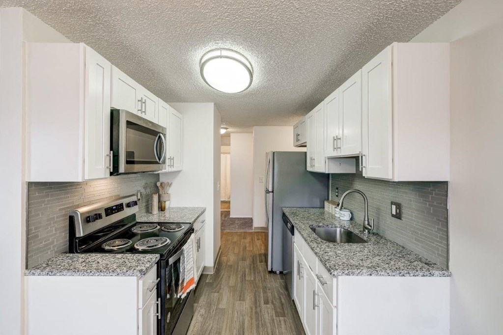 a kitchen with granite counter tops and white cabinets