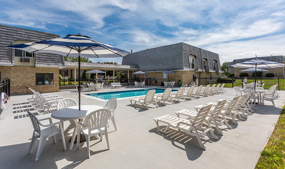 a pool with chairs and umbrellas in front of a building