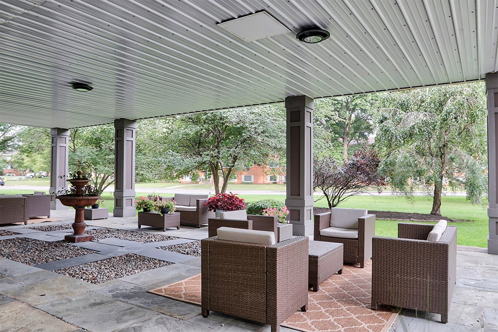 a covered patio with chairs and a fountain