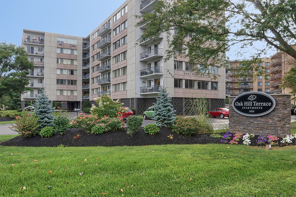 an apartment building with a sign in front of a garden