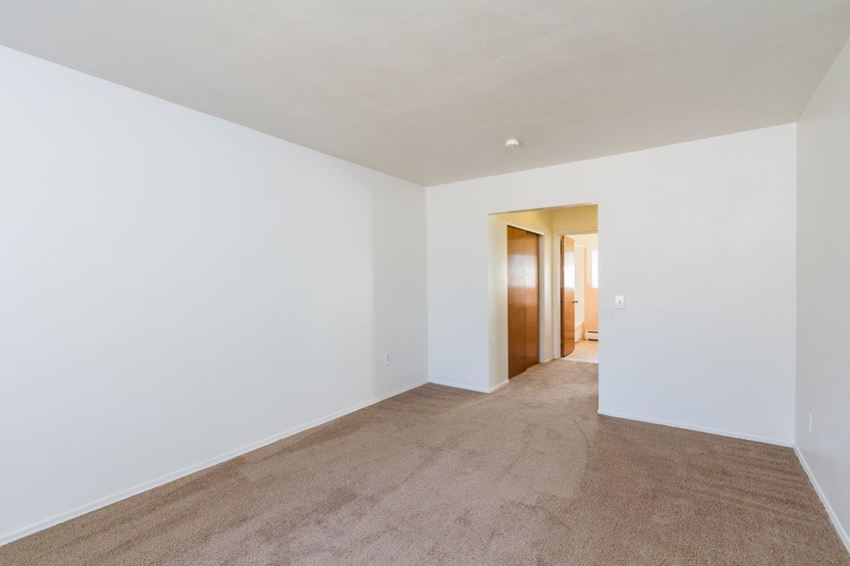 an empty living room with white walls and carpet
