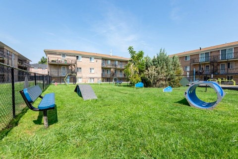 A playground with a blue bench and a blue play structure in front of apartment buildings.